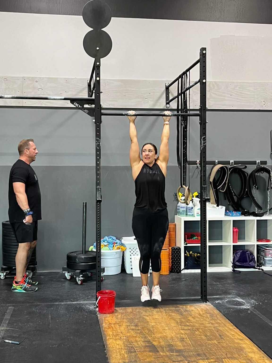 Coach watching an athlete hold a dead hang on the pull-up bar